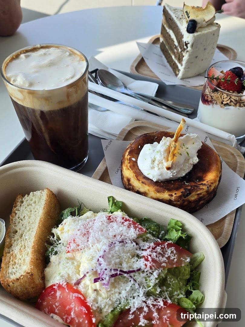 A table setting featuring a layered coffee drink, a slice of cake with cream and fruit topping, a yogurt parfait with granola and berries, a pancake topped with whipped cream and a biscuit stick, and a salad container with bread, tomatoes, greens, and grated cheese.