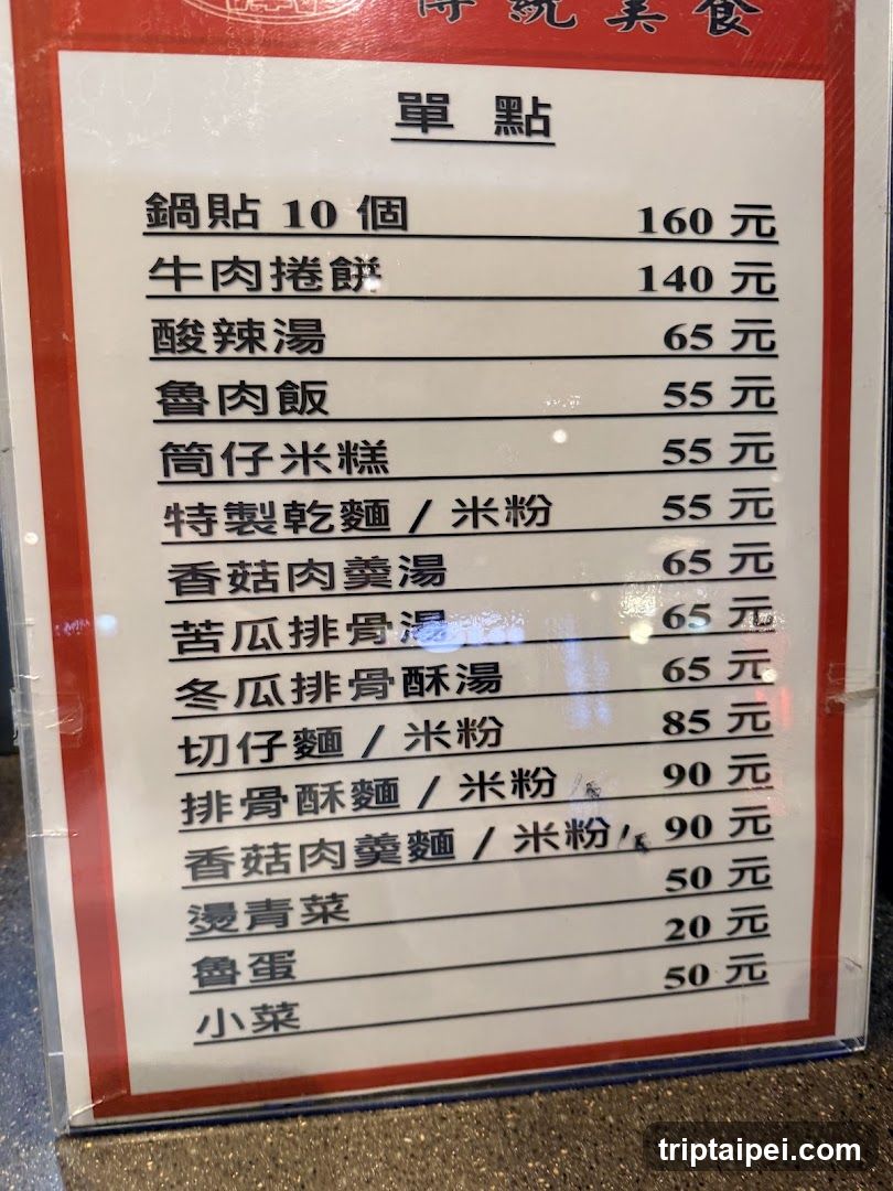 A close-up of a printed menu board with Chinese characters and prices in Traditional Chinese. The menu is titled '單點' (Single Order) and lists various food items such as potstickers, beef rolls, spicy soup, rice dishes, noodles, soups, and side dishes.