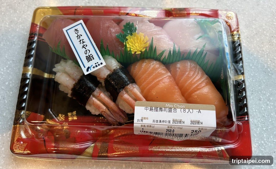 A packaged sushi set containing various types of nigiri sushi, including salmon and shrimp, arranged in a clear plastic container with decorative elements like green grass and yellow flowers.