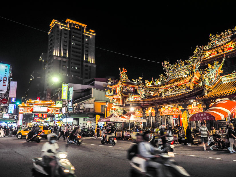 Songshan Ciyou Temple glowing beside the entrance to Raohe Night Market