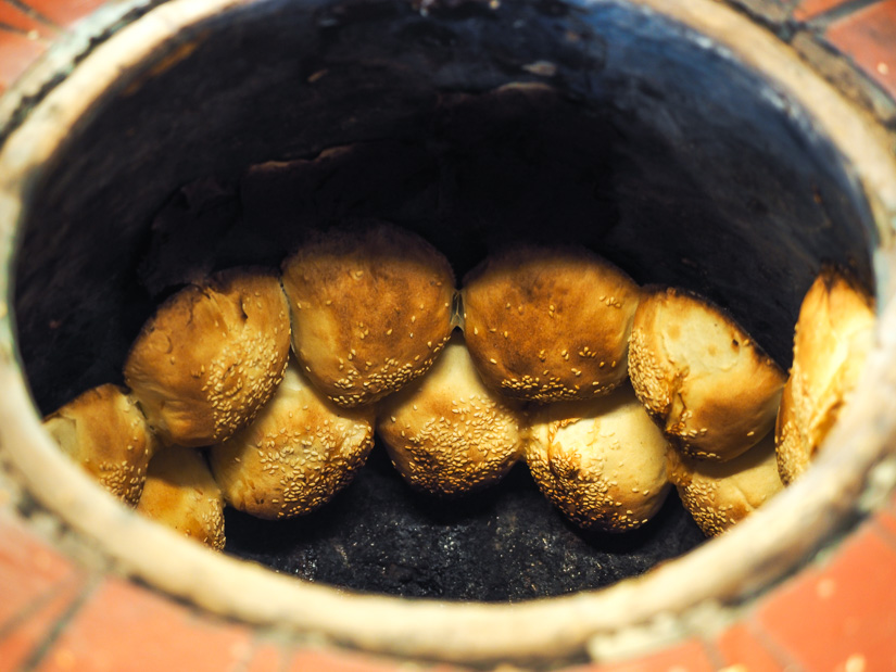 Fuzhou black pepper buns roasting on the inside wall of a clay oven at Raohe